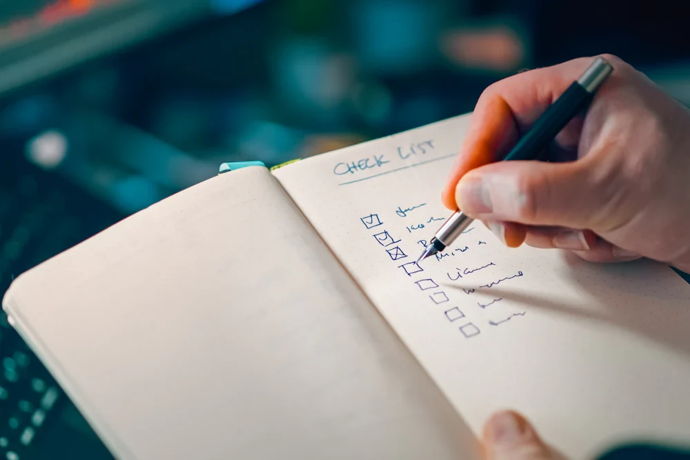 A hand marking a checklist in a notebook