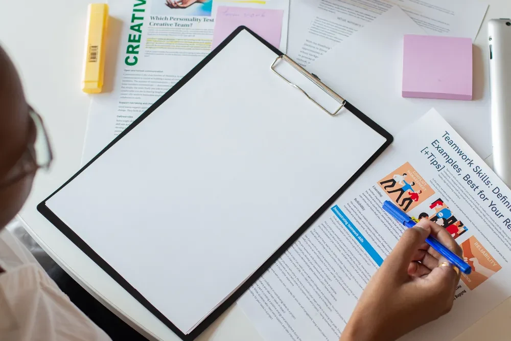 A clipboard and printed documents being reviewed at a desk