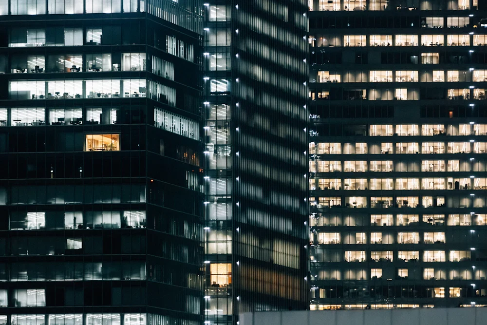 Modern office buildings with illuminated windows at night; illustrative stock photograph