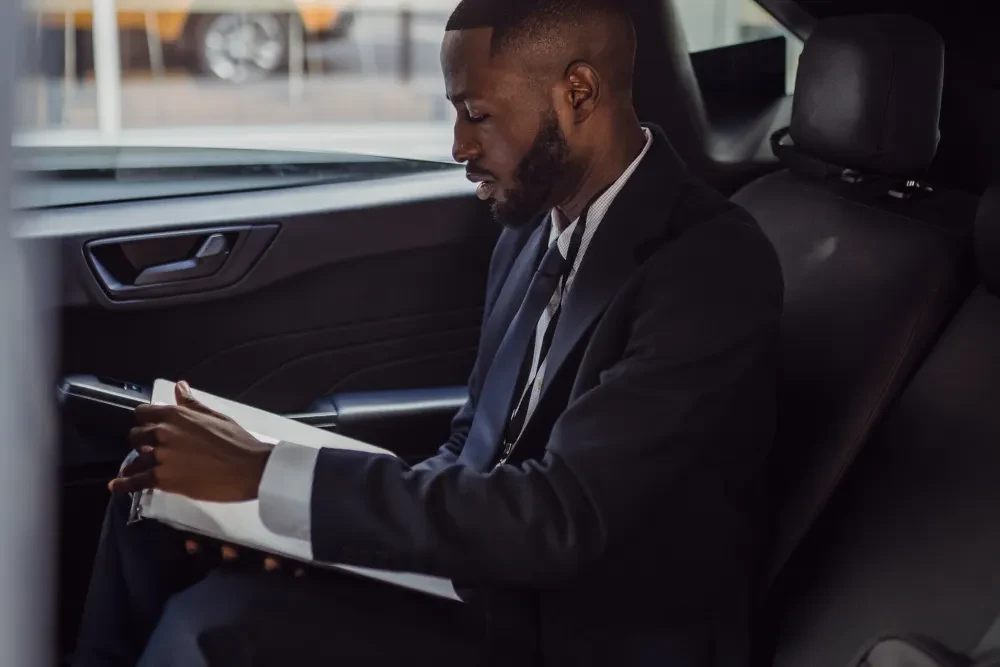 A passenger in a suit reviewing a folder inside a car