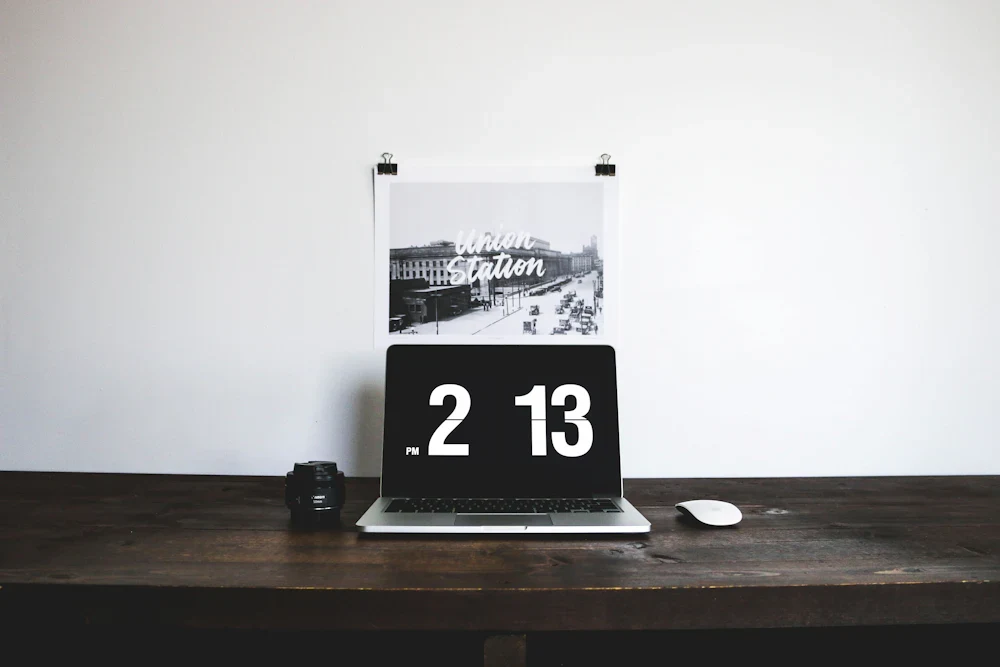 A clock displayed on a laptop on a desk; illustrative stock photograph by Alexis Presa / Unsplash.