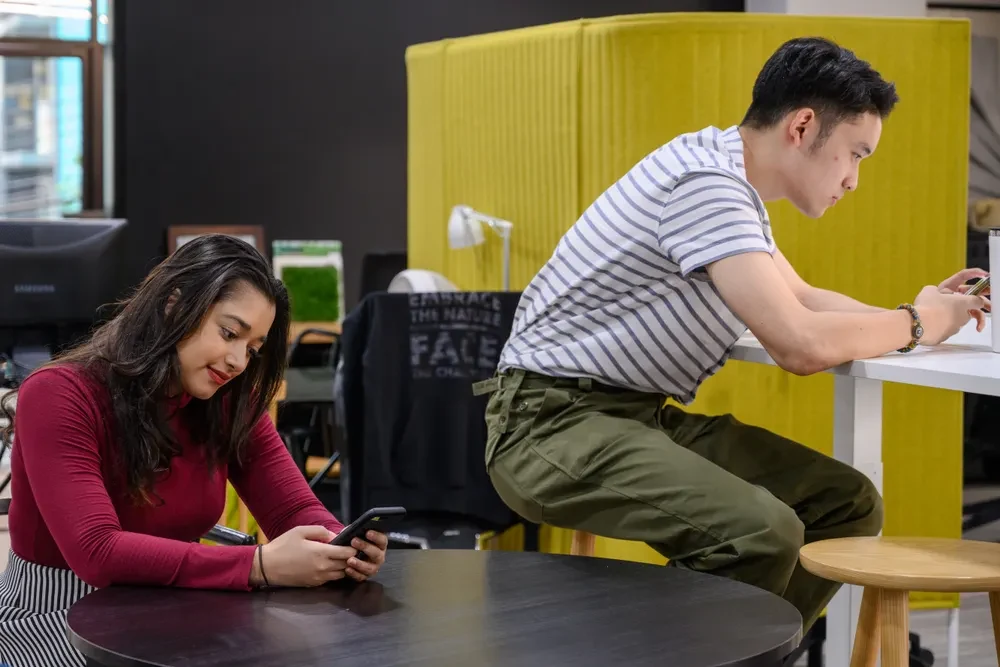 Two people using phones in a shared seating area