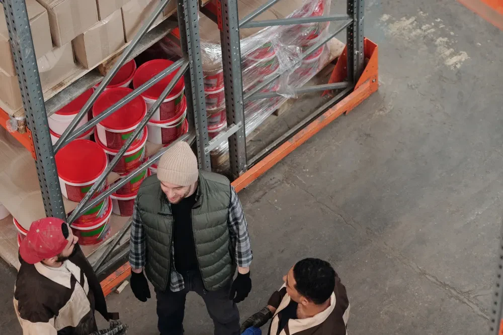 Three people talking beside shelves in a warehouse