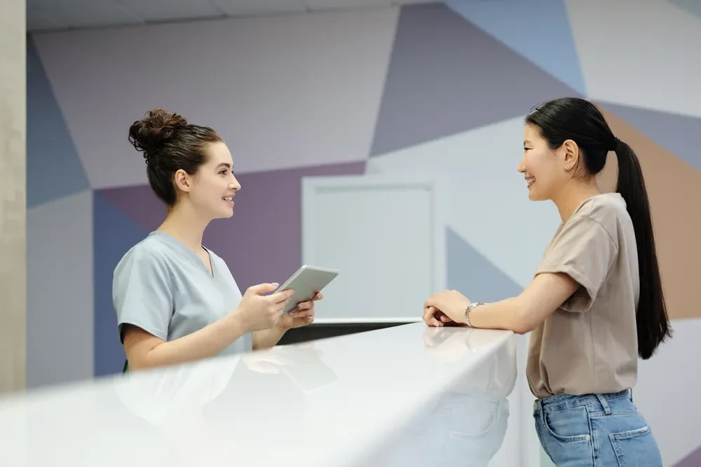 A visitor speaking with staff at a reception desk